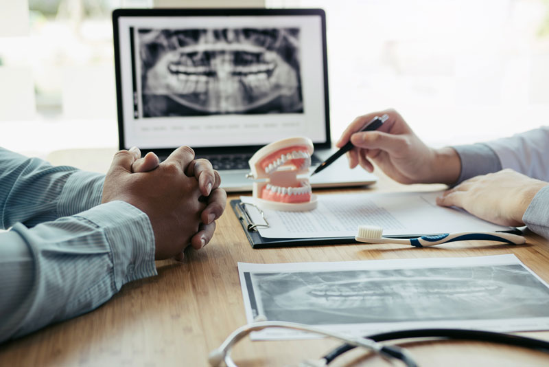 a dental implant dentist and a ptient discuss a dental implant surgery procedure.