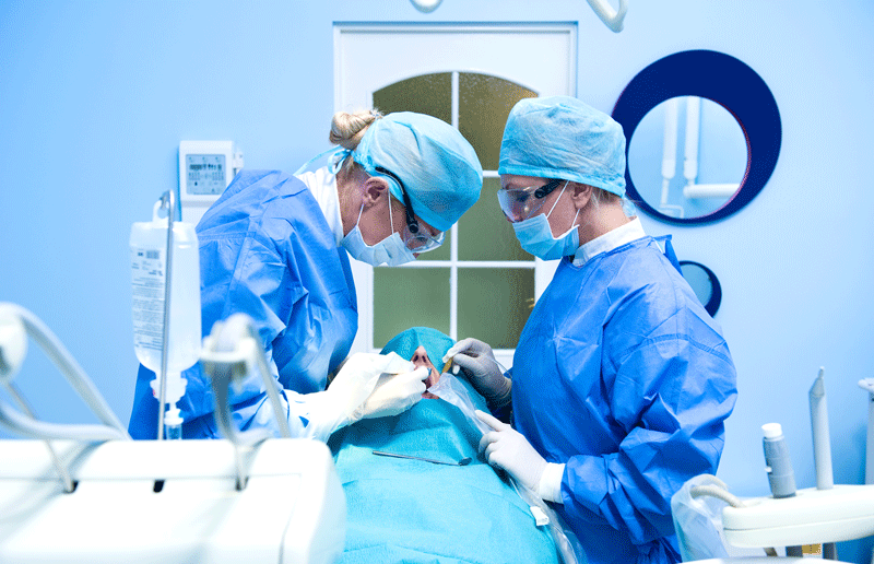 dentist implantologist showing dental bridge implant technology on human tooth jaw model.