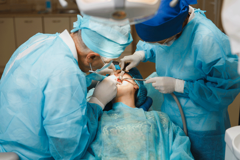 image of an oral surgeon giving a patient dental implants.